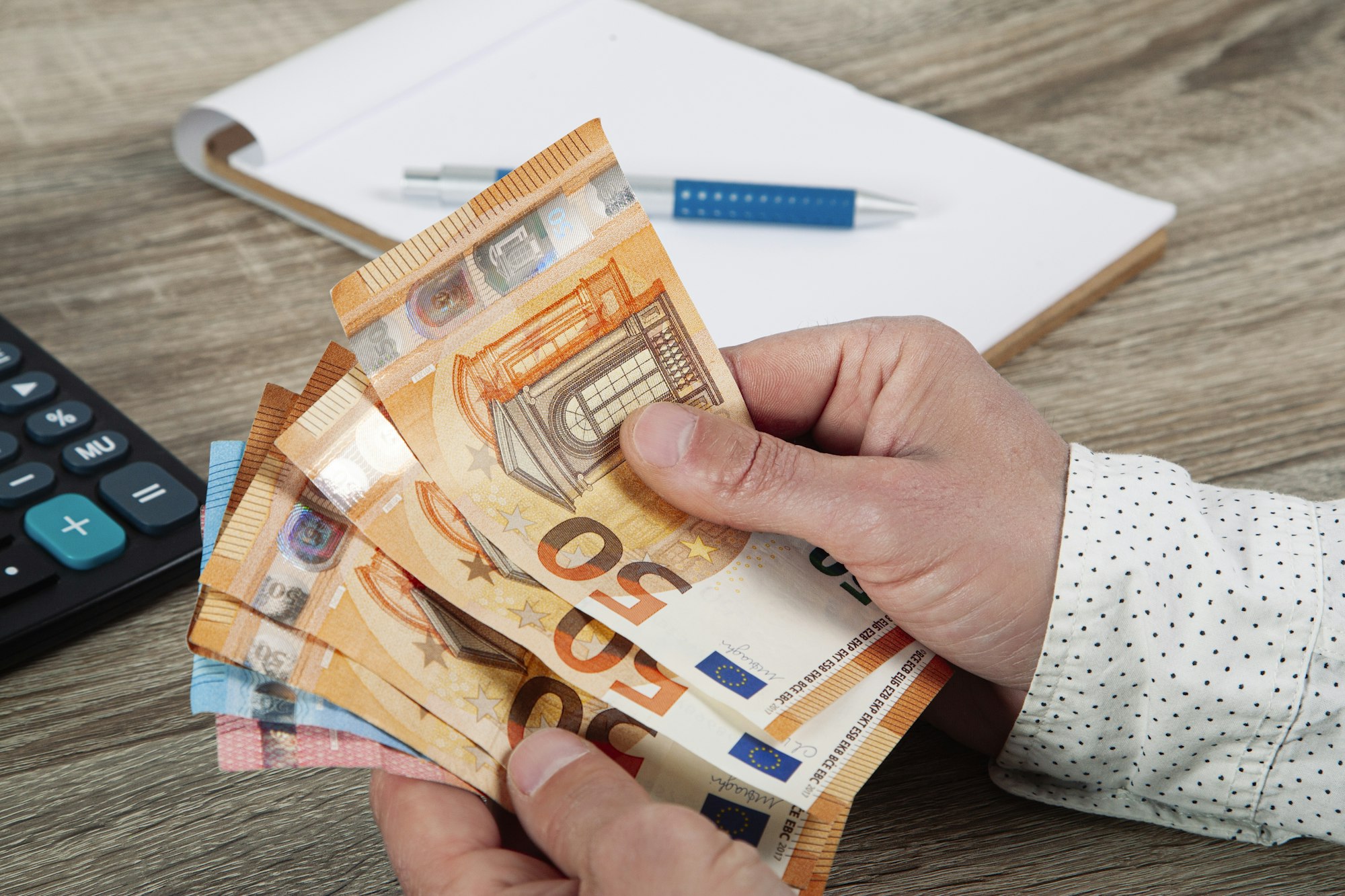 economy and housing concept - man hands with calculator counting money and making notes at home